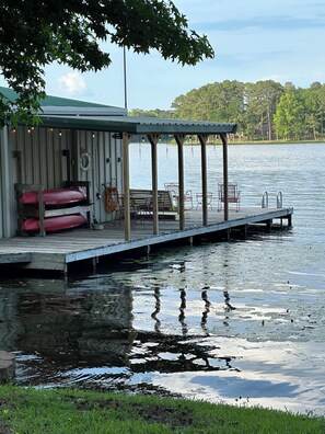 A dock extending into a lake with a covered seating area and a lifebuoy. - Lakehouse, Sleeps 6, Private Dock, Infinity Beach Pit, 2 Kayaks! (Hawkins)
