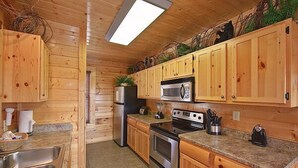 A wooden cabin-style kitchen with a refrigerator, microwave, stove, and sink. - Time Well Wasted | Hot Tub, Game, Loft, Resort Pool, Views & Family-Friendly (Sevierville)