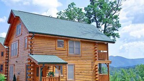 A log cabin with a porch, multiple windows, and a stone foundation. - Time Well Wasted | Hot Tub, Game, Loft, Resort Pool, Views & Family-Friendly (Sevierville)
