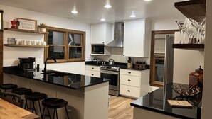 Een moderne keuken met een centraal eiland, barstoelen en een eettafel.
