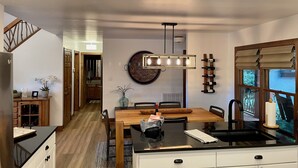 Een moderne keuken met een centraal eiland, een houten eettafel en inbouwapparatuur.