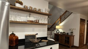 Een keuken met een koelkast, houten planken en een trap.
