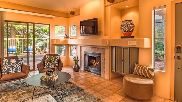 A spacious living room with a fireplace, comfortable seating, and large windows offering a view of the outdoors. - Jewel House West Sedona with Private Hot Tub! (Sedona)