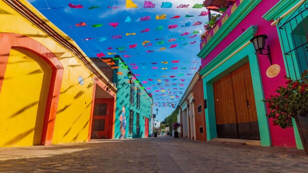 A cobblestone street lined with colorful buildings, a clear sky, and hanging decorations.
