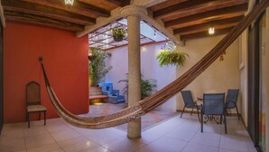 A hammock in a room with a tiled floor, a chair, and a table.