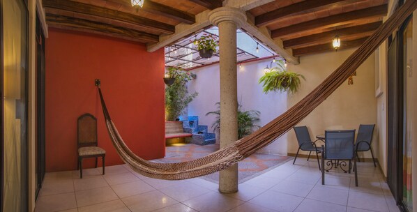 A hammock in a room with a tiled floor, a chair, and a table.