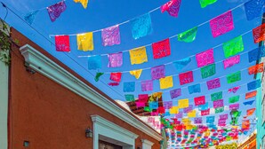 A cobblestone street with colorful flags hanging overhead.