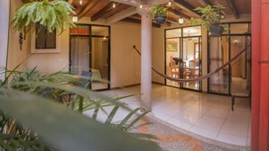 A spacious indoor area with a high ceiling, exposed wooden beams, and hanging plants.