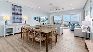Un salón amplio con una mesa de comedor, sillas y un sofá. Una ventana grande ofrece vistas al exterior.