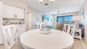 Una cocina moderna con muebles blancos, una mesa de comedor con sillas y una araña.