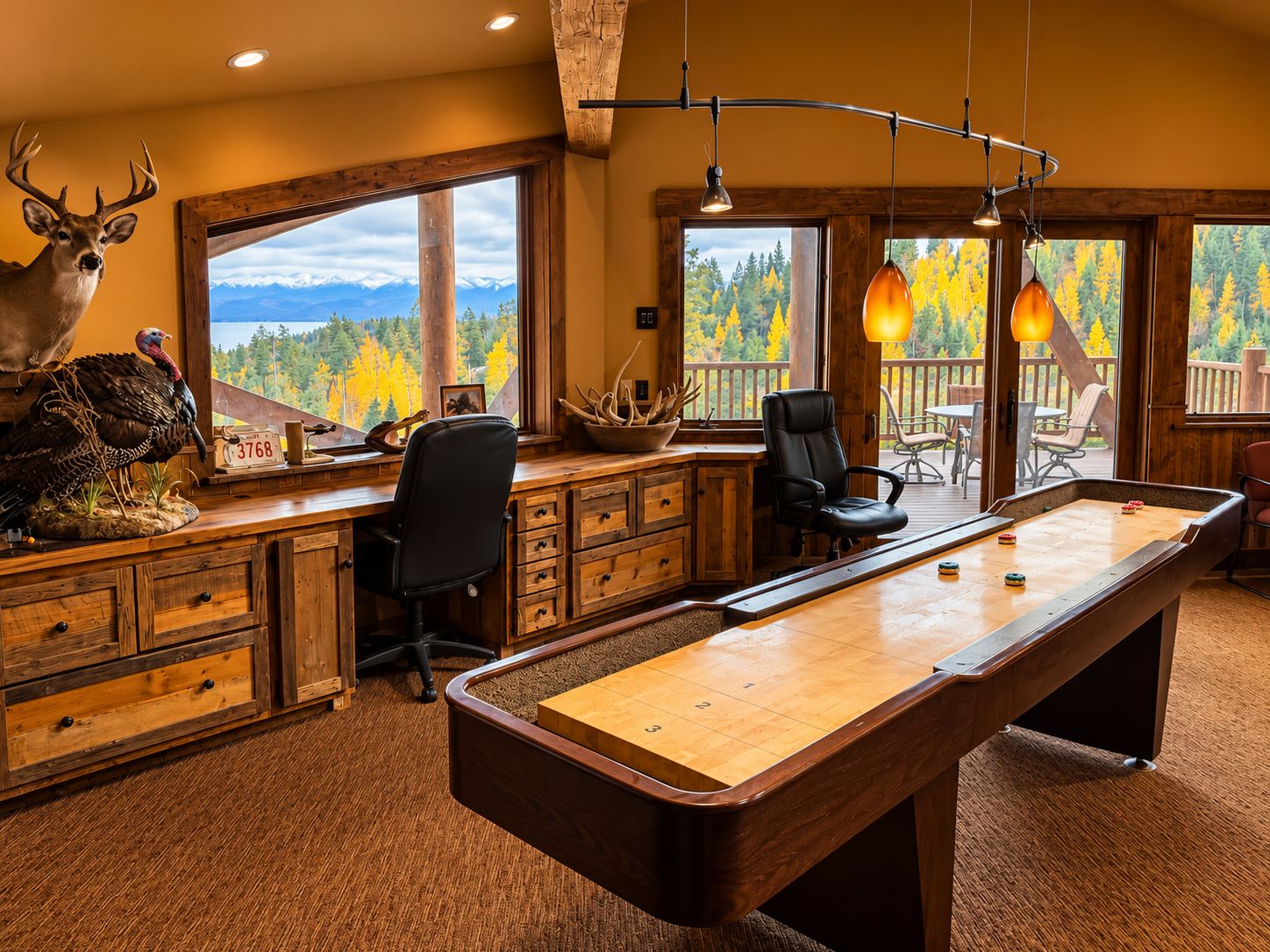 A pool table in a room with wooden cabinets, a desk, and a view of a forest through large windows.