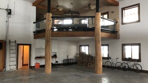 A spacious loft with a high ceiling, exposed wooden beams, and a mezzanine level.