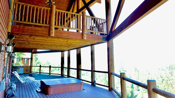 A wooden deck with a hot tub, lounge chairs, and a barbecue grill.