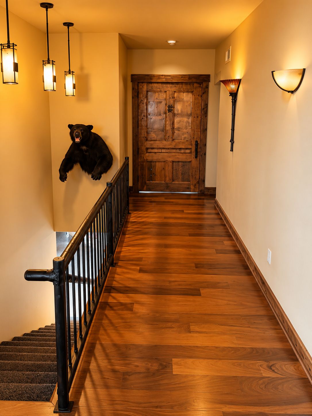 A wooden staircase with a bear mounted on the wall, a wooden door at the top, and wall-mounted lighting fixtures.