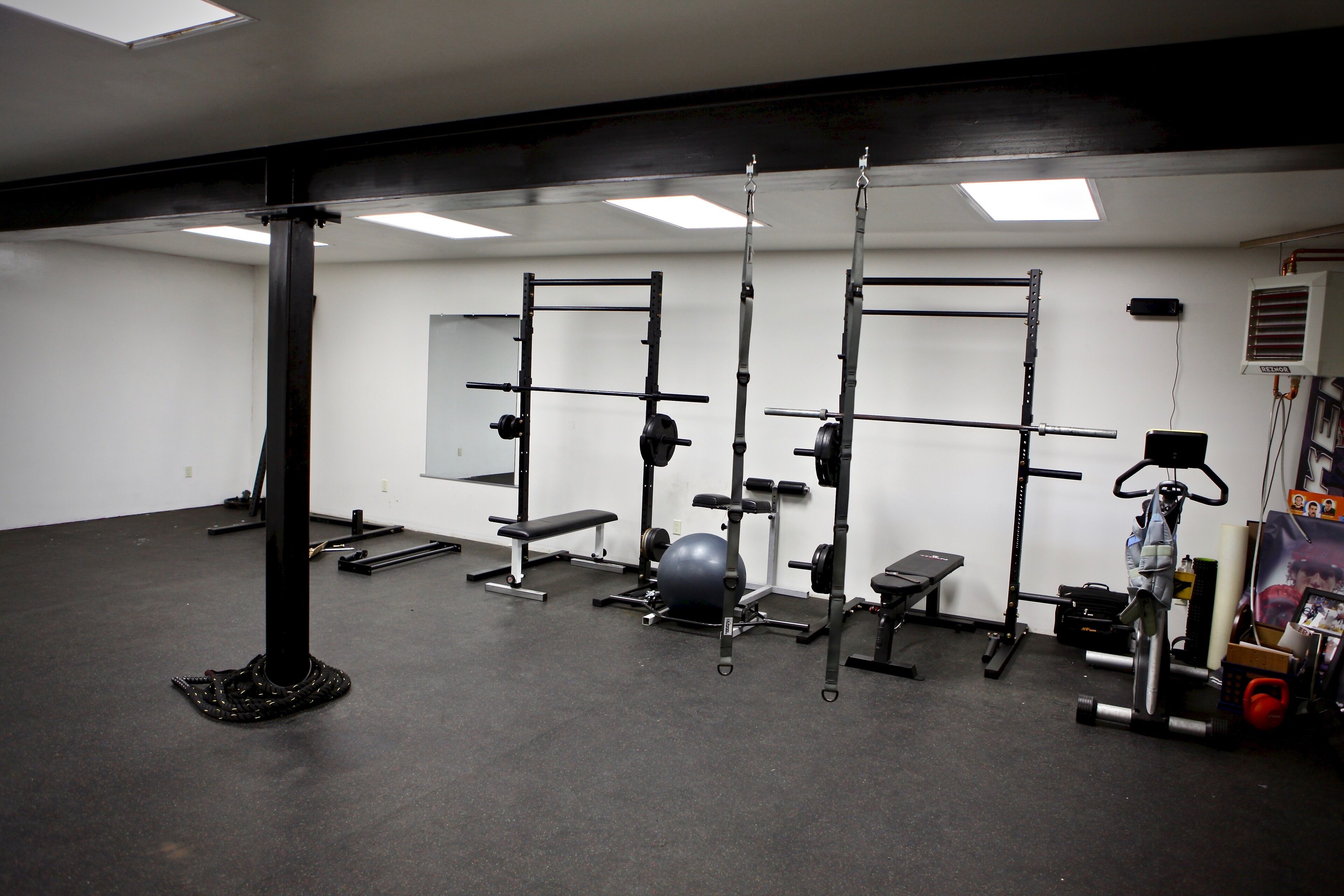 A gym with weightlifting equipment, benches, and a large exercise ball.