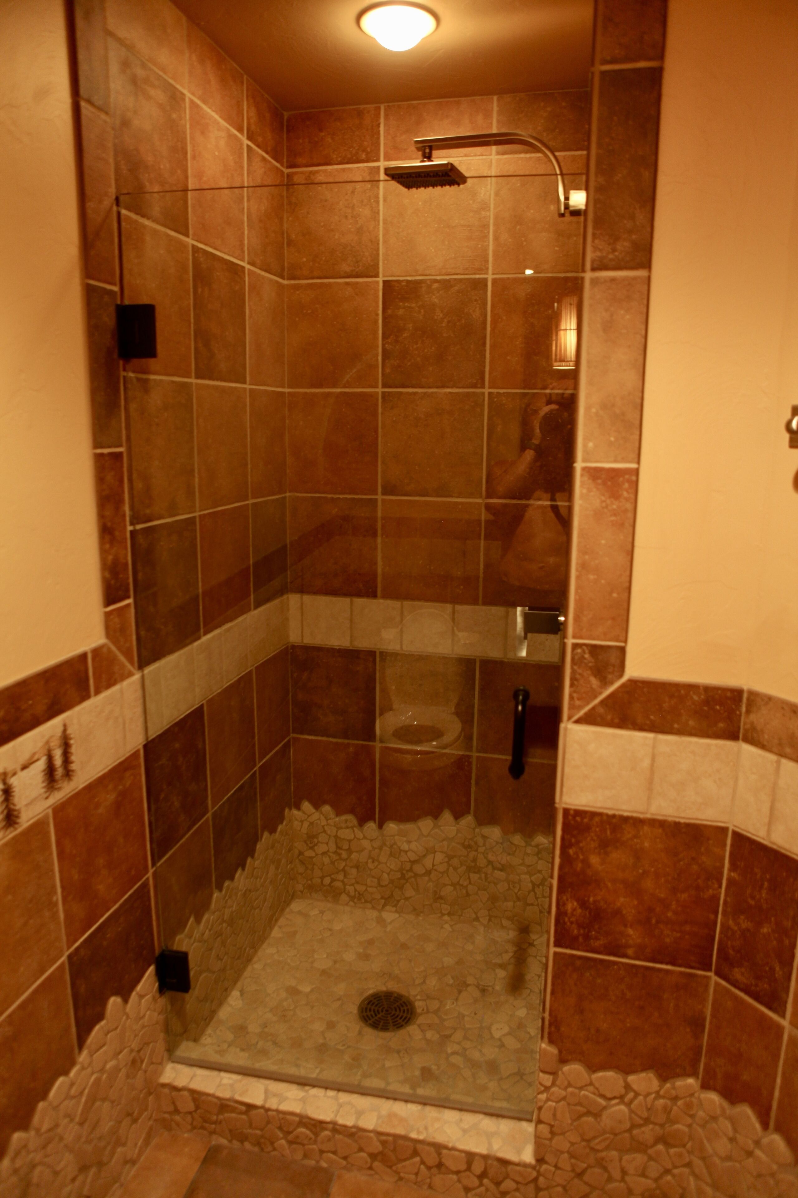 Un área de ducha con paredes de azulejos y puerta de cristal.