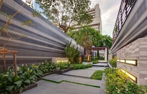Stroll through the serene outdoor corridor, lined with lush greenery and a striking striped pattern.