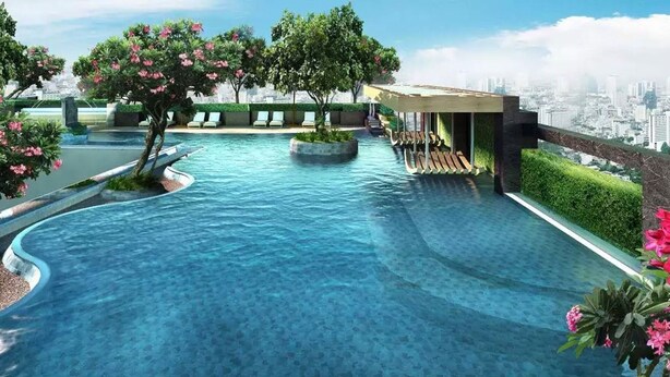 Una piscina moderna con vista a la ciudad, rodeada de exuberante vegetación y flores rosadas.