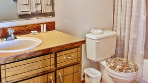 Een badkamer met een houten wastafelmeubel, een wastafel, een toilet en een spiegel.
