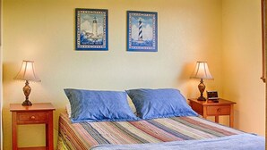 Een hotelkamer met een bed, twee nachtkastjes, twee lampen en twee foto's in lijsten aan de muur.