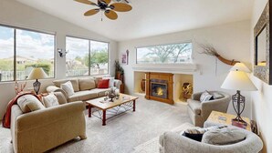 A spacious living room with a fireplace, large windows, and a ceiling fan. - Mountain Calling spectacular views/ Spacious 3 BR Home/ Oro Valley/ Tucson (Tucson)