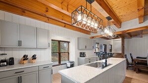 Una cocina moderna con armarios blancos, una isla central con pileta y techo de madera.