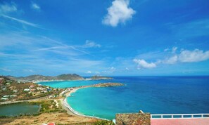 A coastal landscape with a clear blue sky, a beach, and a view of the ocean.