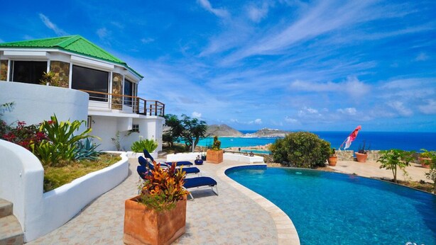 A modern house with a pool, a view of the ocean, and a clear sky. - 🌴Joy Estate by IRE Vacations - Expansive Property with Amazing Views ☀️ (Cay Hill)