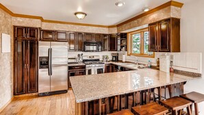 A modern kitchen with dark wood cabinets, stainless steel appliances, and a granite countertop.
