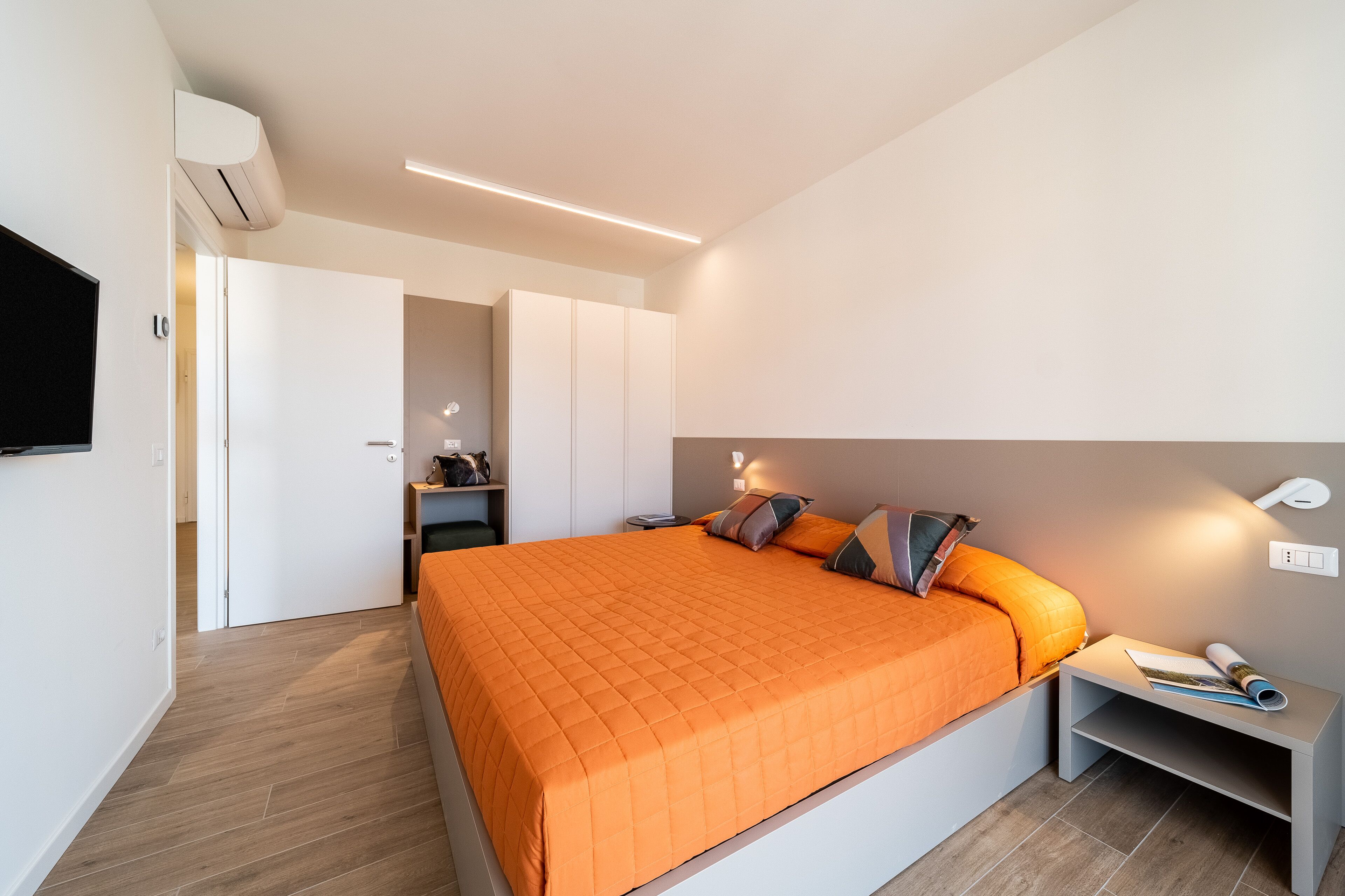 Une chambre moderne avec un grand lit, une table de chevet avec une lampe et une armoire.