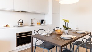 Een moderne keuken met witte kasten, een ingebouwde oven en een eethoek met een tafel gedekt voor twee personen.