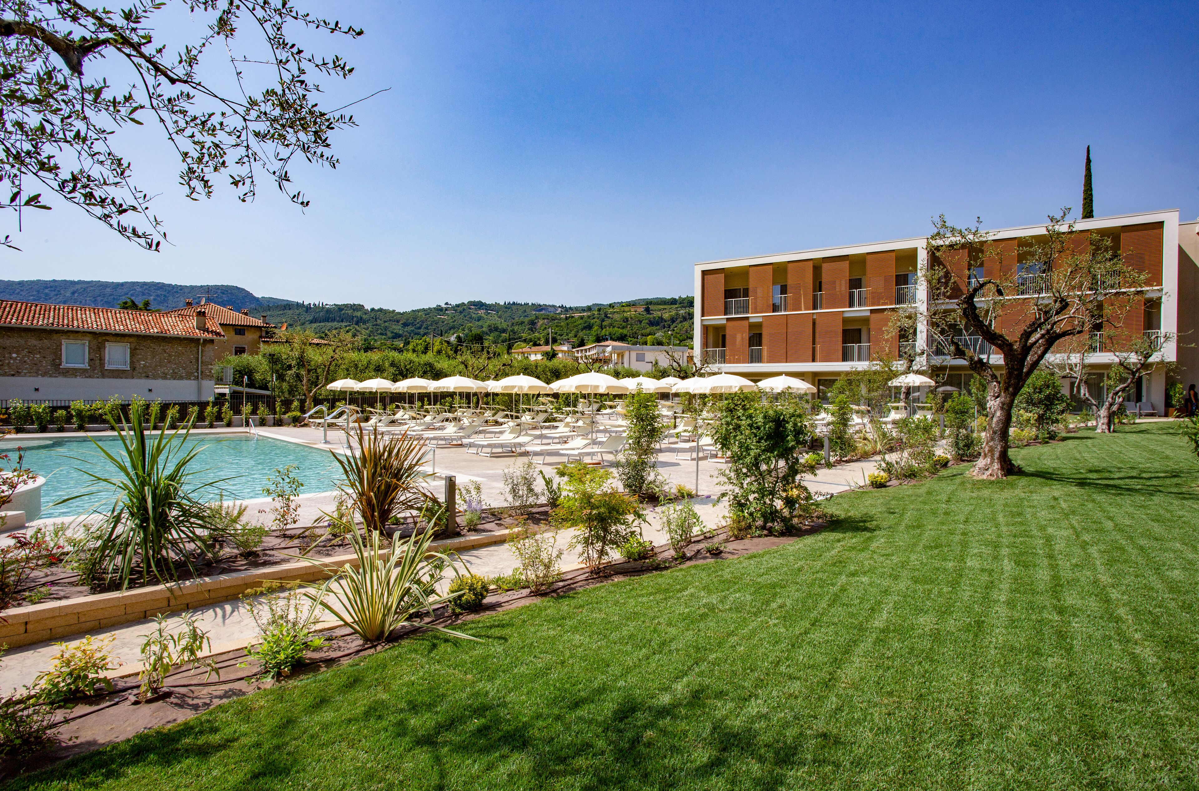 A hotel with a swimming pool, outdoor seating, and a view of the hills.