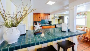 Eine Küche mit einer grüngranitartigen Arbeitsplatte, weißen Schränken und einem weißen Kühlschrank.