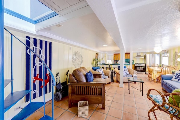 A spacious living area with a high ceiling, a dining area, and a kitchen.