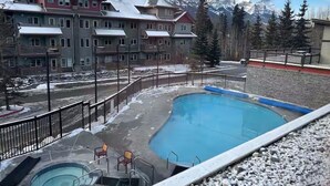 Un hotel con piscina, jacuzzi y vistas a montañas nevadas.