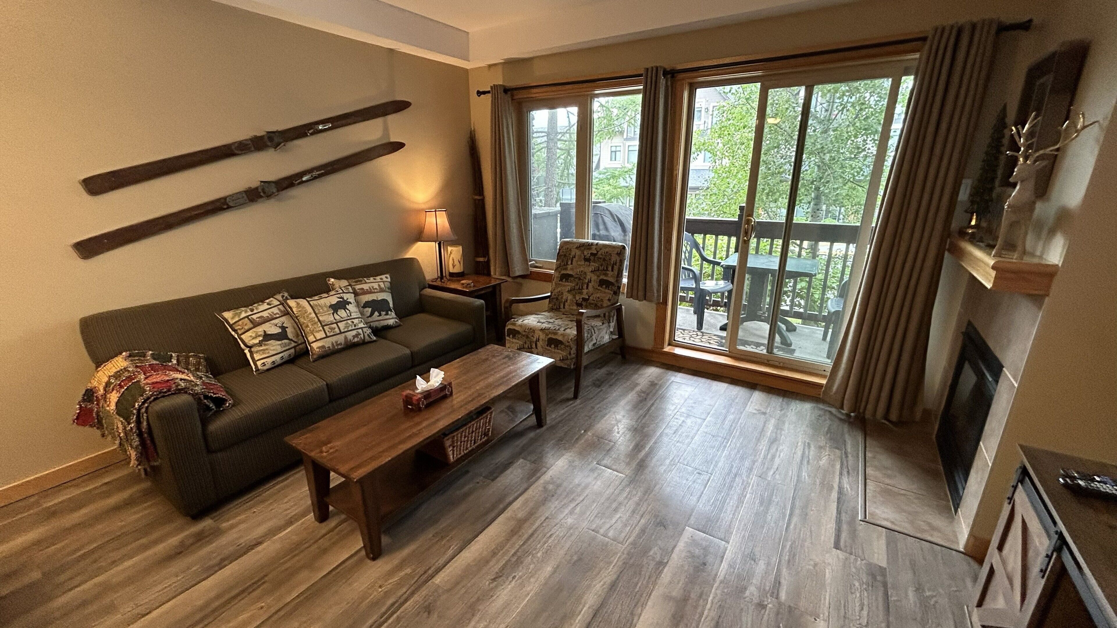 Sala de estar con sofá, sillón y mesa de centro, chimenea y vistas a través de amplios ventanales.