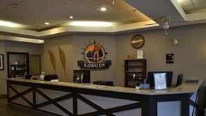 Un mostrador de recepción con un logotipo, un reloj y un certificado en el marco en la pared.