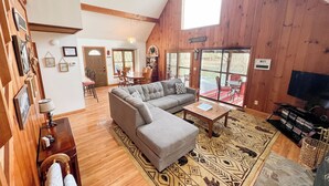 Een gezellig interieur van een chalet met een hoekbank, een eettafel en een televisie.
