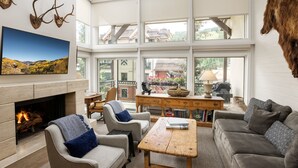 A spacious living room with a fireplace, comfortable seating, and large windows offering views of the outdoors. - Montaneros 410 - 3 Bedroom Diamond (Vail)