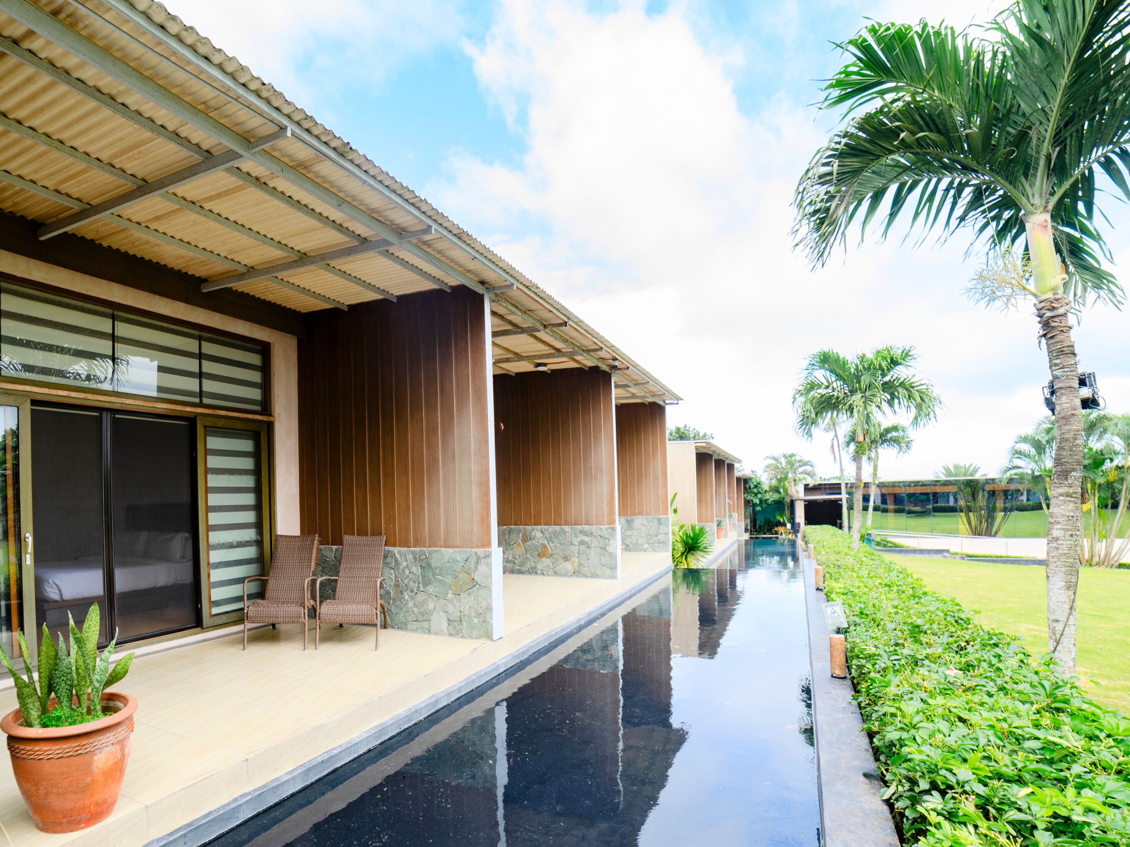 A hotel with a pool, palm trees, and a covered walkway.