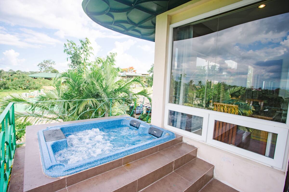 A hot tub on a balcony with a view of the surrounding greenery and buildings.