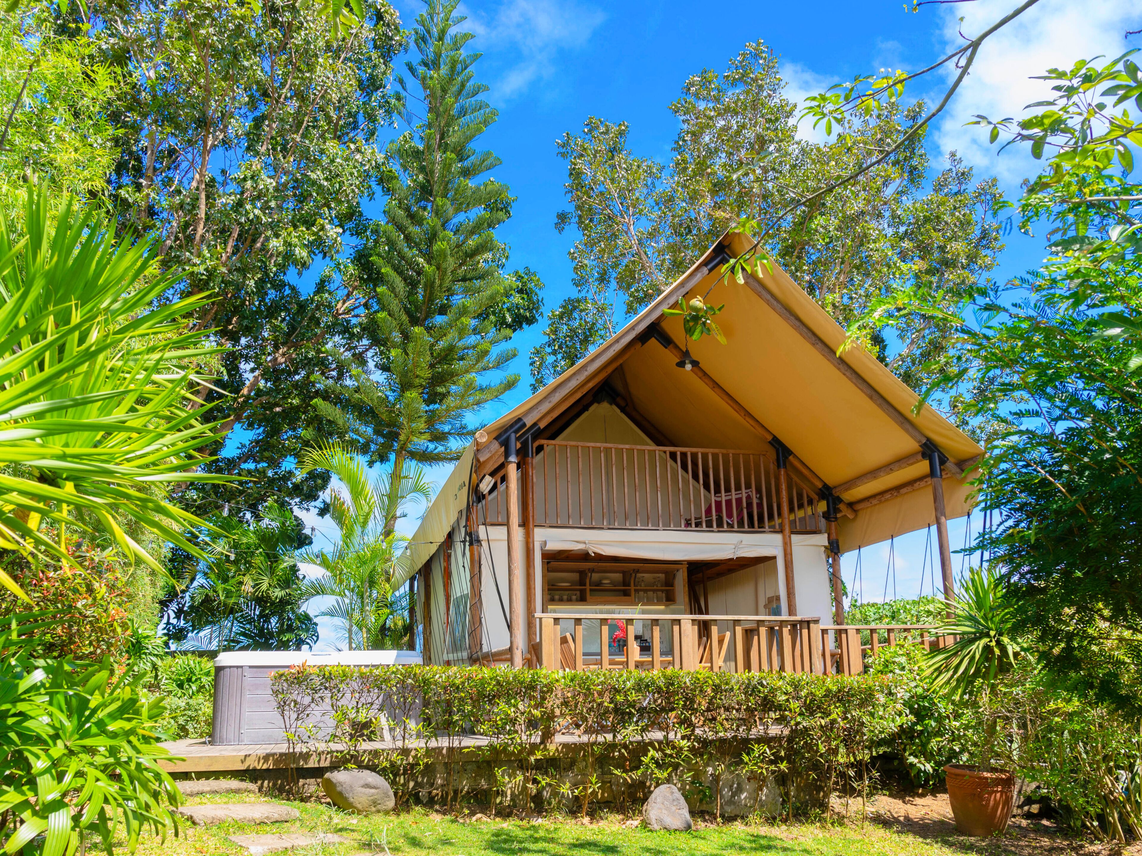 A two-story building with a balcony, surrounded by lush greenery and trees.