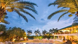 A pool area with palm trees, outdoor seating, and a building with balconies. - The Park - Silang (Silang)