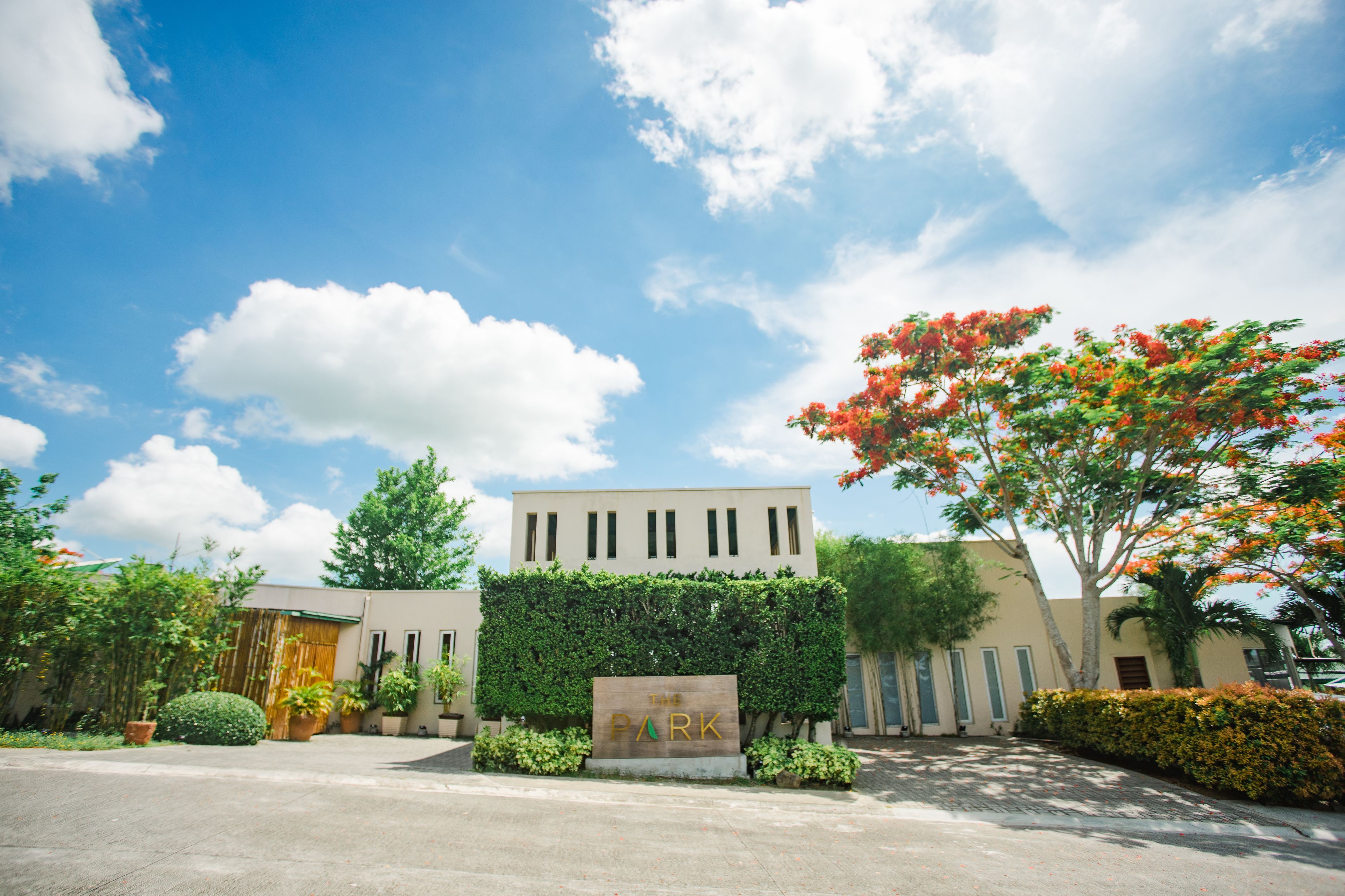 A building with a sign reading "THE PARK" surrounded by greenery and trees.