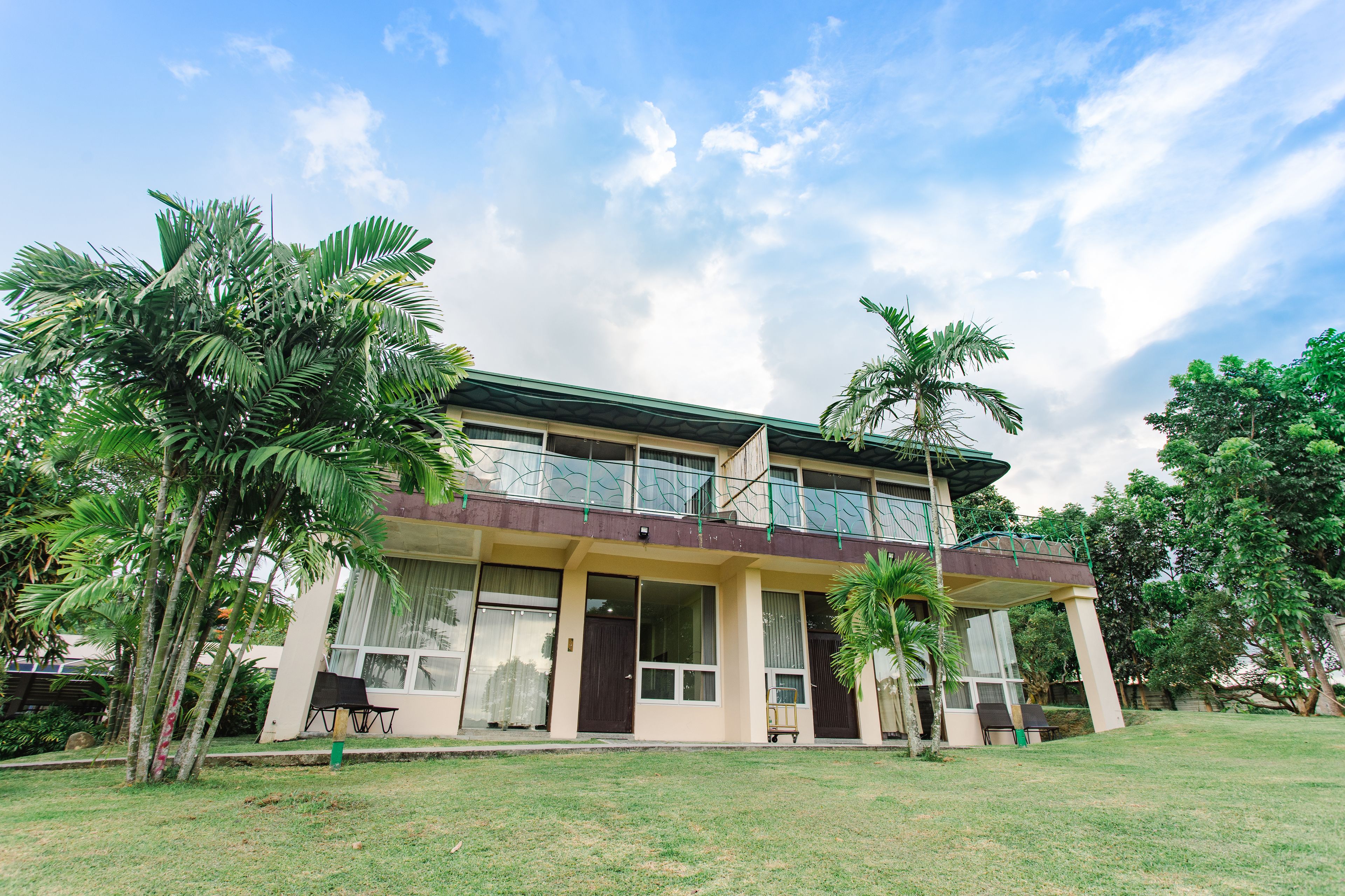 A two-story building with a flat roof, large windows, and a balcony.