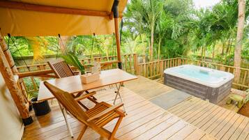 A wooden deck with a hot tub, a table, and chairs.