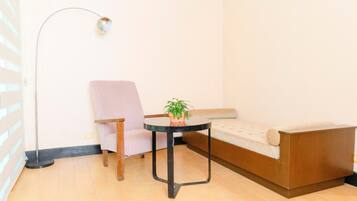 Una habitación con sofá, sillón, una mesita con planta y lámpara de pie.