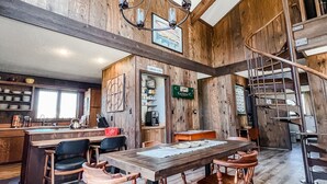 Una cocina amplia con vigas de madera, un comedor con sillas de madera y una escalera que lleva a un nivel superior.