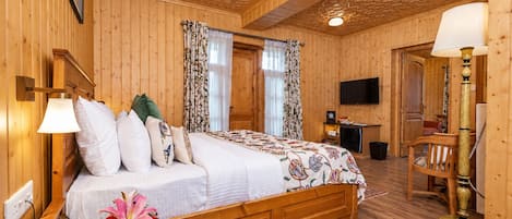 Una habitación con piso de madera, una cama, un escritorio, una silla y un televisor.
