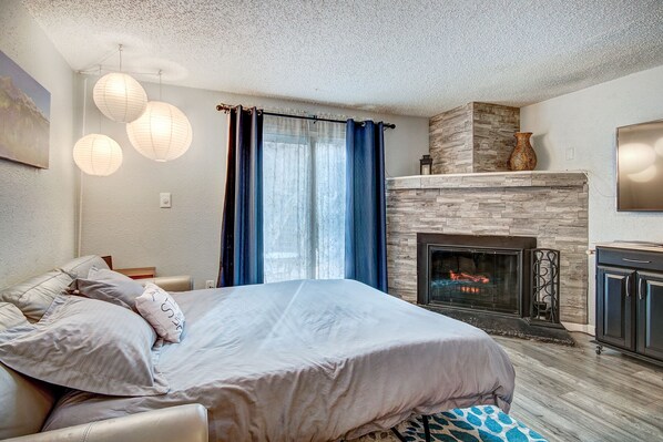 Ein Schlafzimmer mit einem Bett, einem Kamin und einer Steinwand.